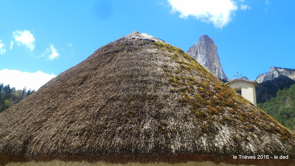 Toit de chaume de la Chapelle sur fond de monolithe