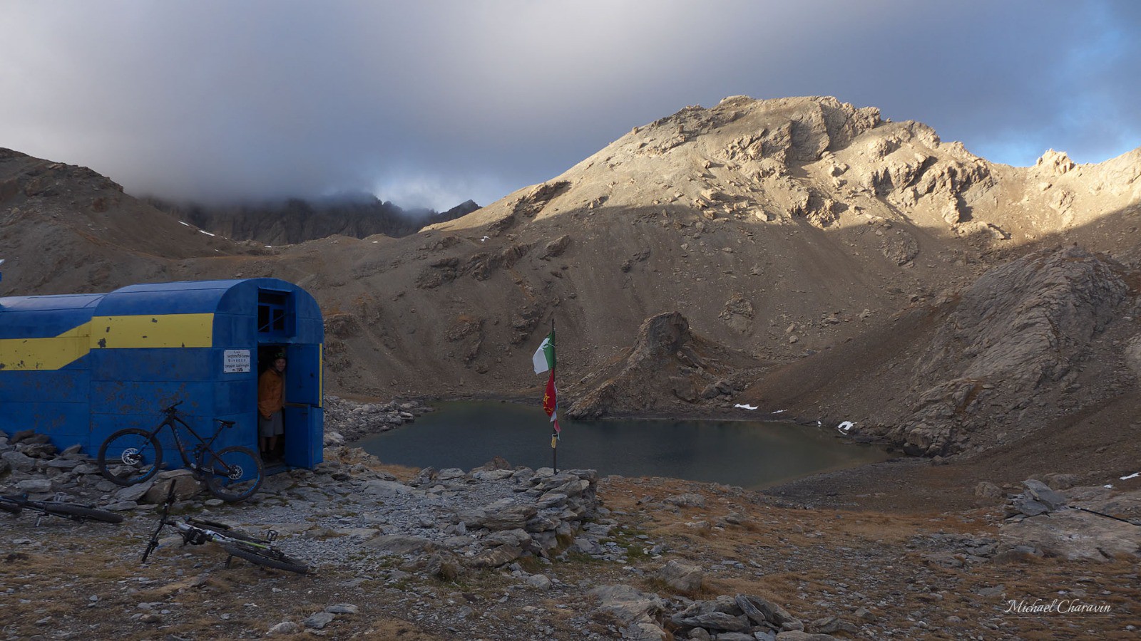 Bivacco Barenghi (2822 m). Un dernier rayon de soleil éclaire la Tête de la Fréma, des nuages accrochent le sommet des Aiguilles de Chambeyron.